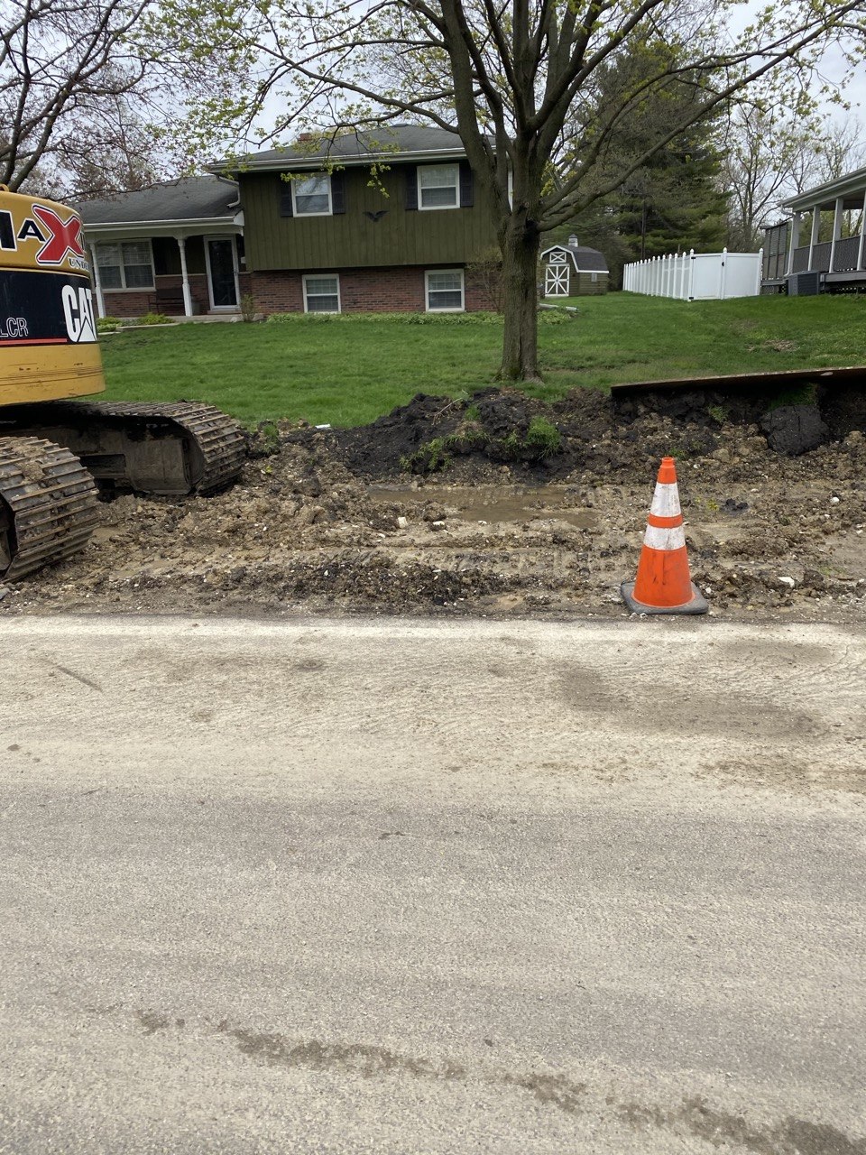 CAT excavator at curbside with open trench