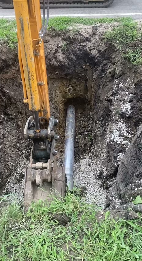 Excavator installing large pipe in gravel bed